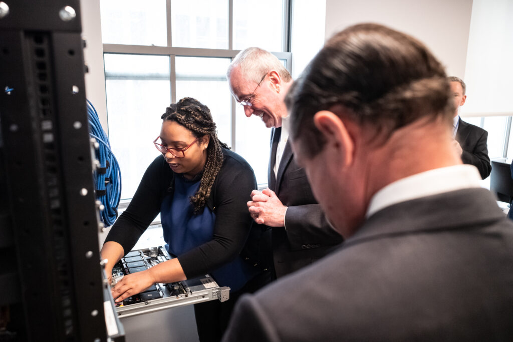 a young black technologist and two white older technologists examine business technology hardware