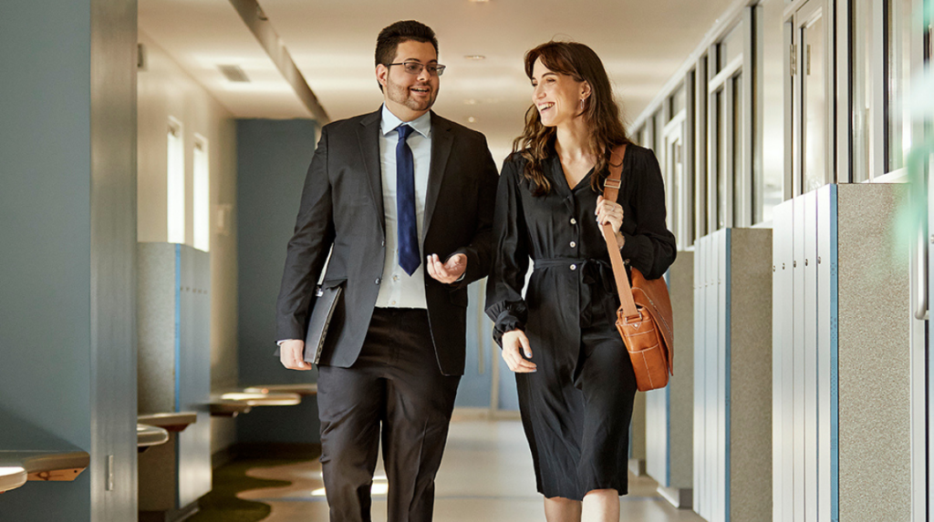 two people walk down a hallway together, talking 