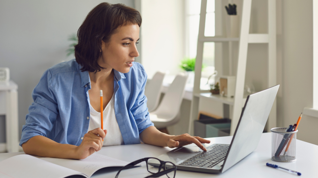 a woman sits at a desk examining a computer screen