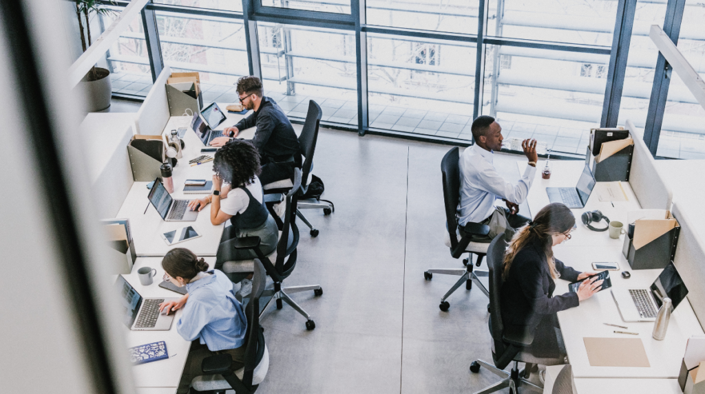 several individuals sit at desks in a workspace