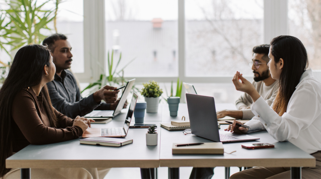 several individuals sit around a conference table in a workspace