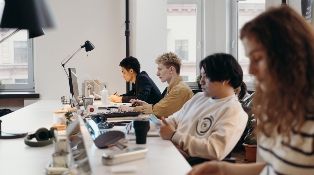 several individuals sit at a desk in a workspace