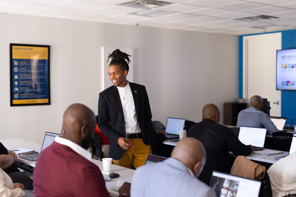 a black man stands in a classroom full of students