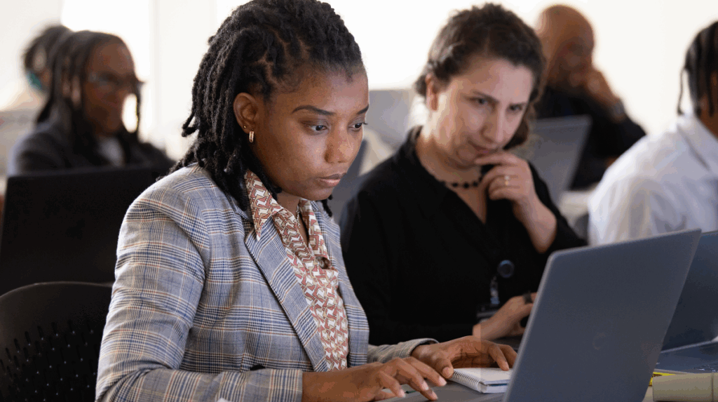 two women sit facing computer screens in a classroom