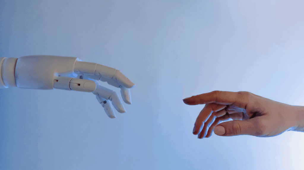two hands, one human and one robot reach to touch one another