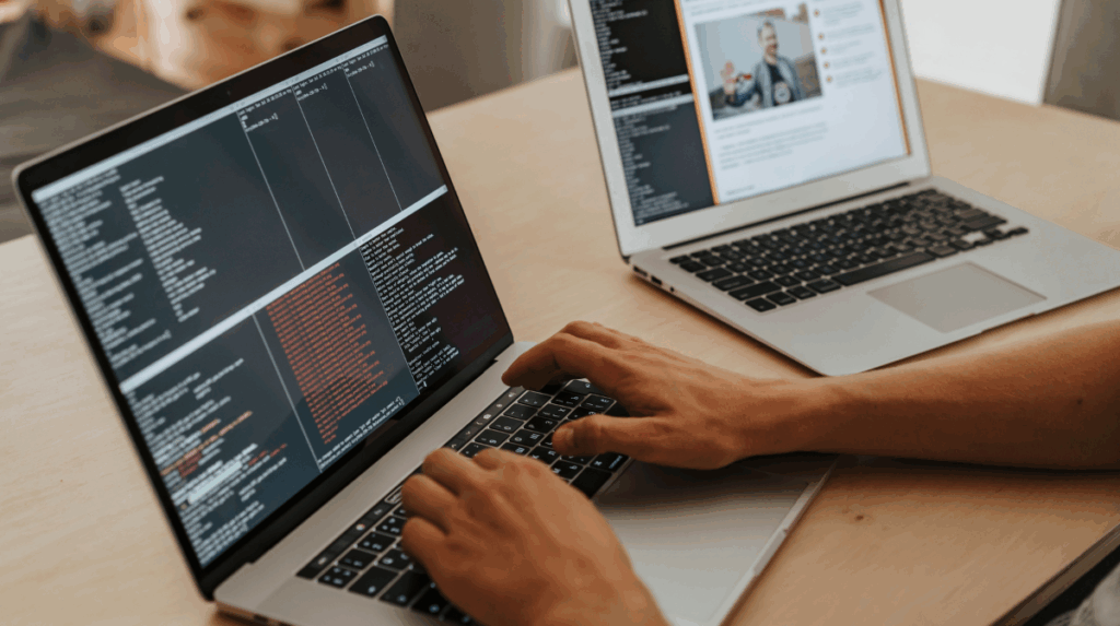 hands stretch across a laptop keyboard, coding is shown on the screen