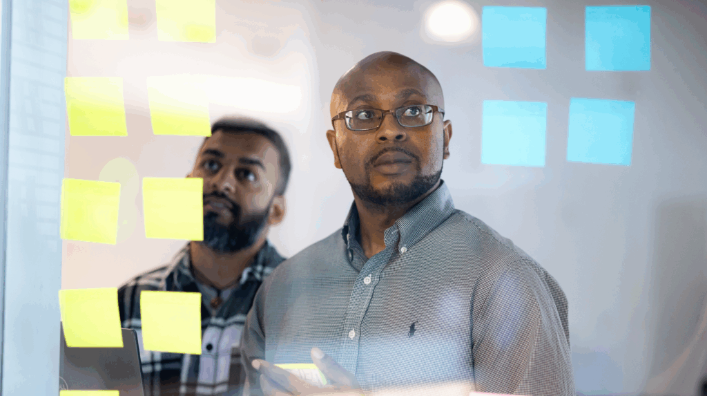 Two professionals looking at sticky notes, collaborating on strategy