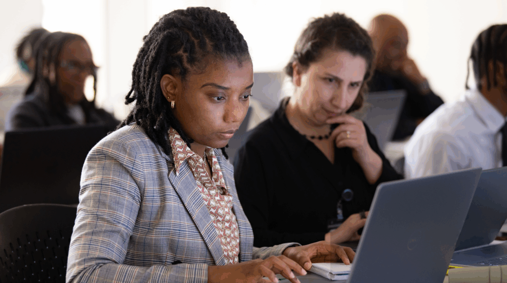 Two technologists looking at a laptop in a workforce development setting