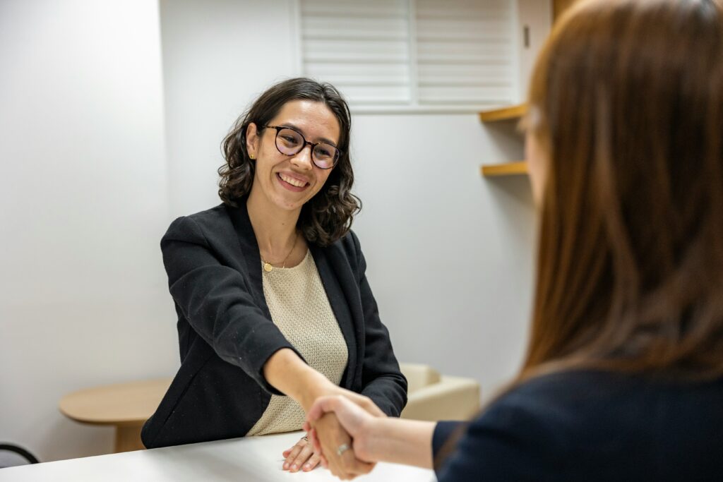 Hiring manager shakes hands with a job candidate during an interview