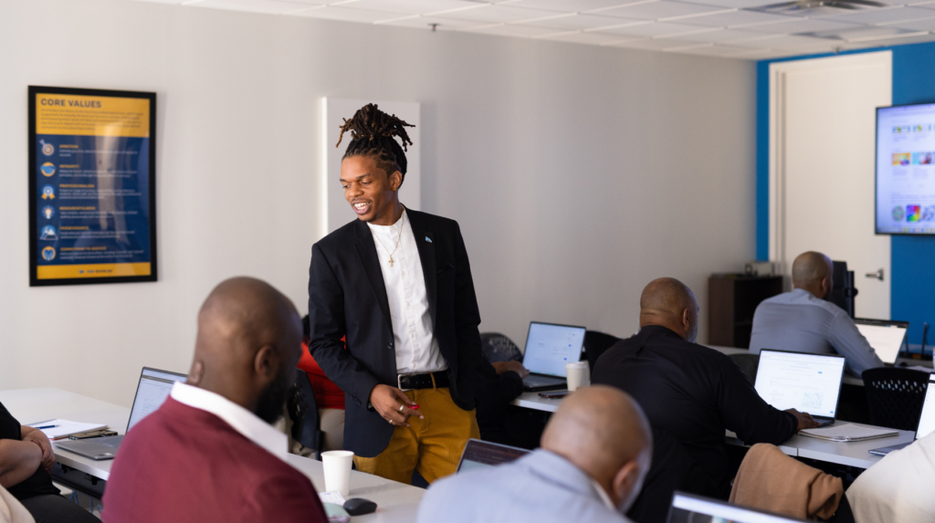 Per Scholas instructor conducting hands-on technical training with adult learners
