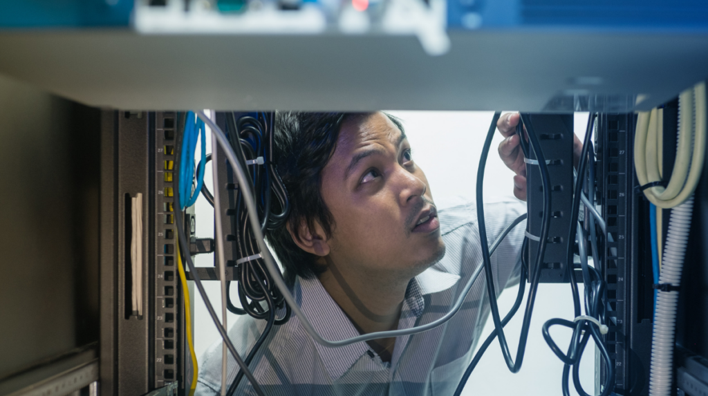Technician managing network cabling inside a server rack in a data center