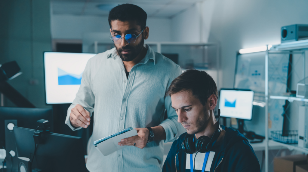 Two IT security professionals collaborating on system analytics in a technology operations center