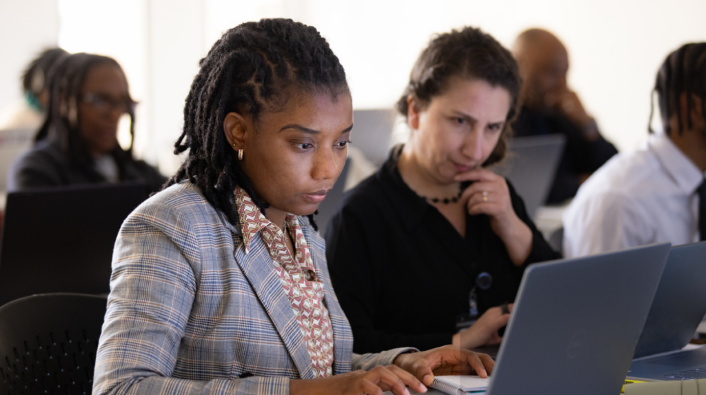 Two professionals working on laptops in a cybersecurity workforce training program